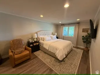 Recessed lighting, crown molding, wood-finish flooring, and a window with drapes