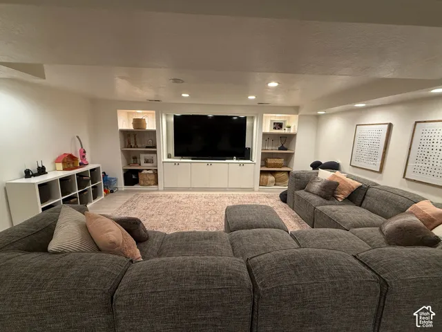 Recessed lighting illuminates the space, featuring built-in cabinetry with integrated shelving and a media console