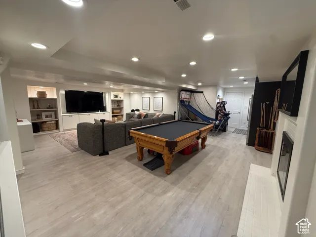 Recessed lighting, wood-finish flooring, built-in media center, built-in shelving, and a white fireplace