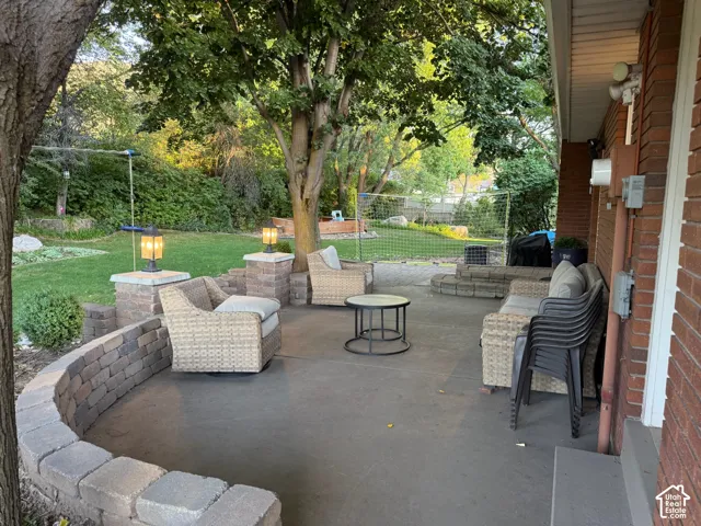 Paved patio with a curved stone-block retaining wall, brick exterior, and lush green lawn