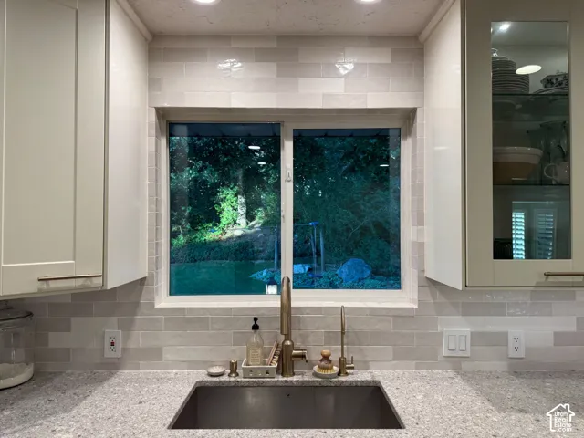 Stainless steel undermount sink with a brass-tone faucet, complemented by a light-toned countertop and a subway tile backsplash