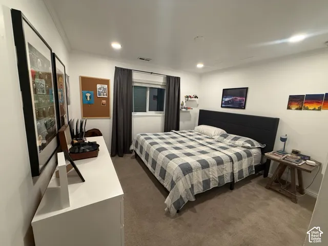Recessed lighting illuminates a space featuring a window with dark drapes, wall-to-wall carpeting, and a white dresser