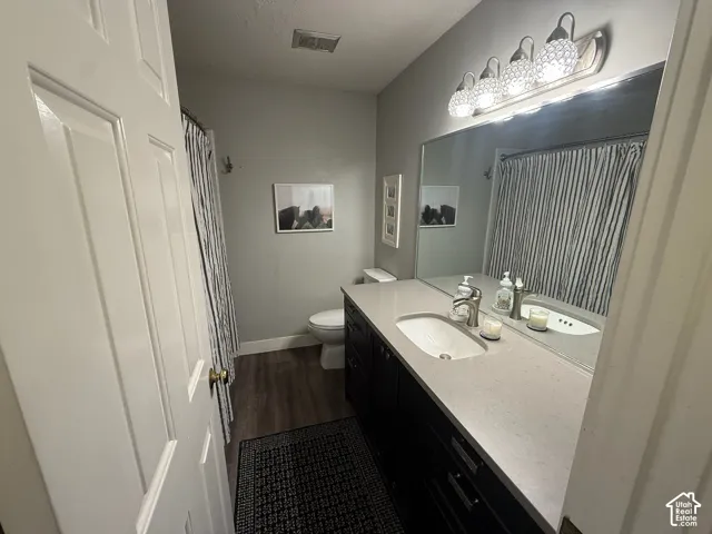 White paneled door, wood-finish flooring, dark wood vanity with white countertop, integrated sink, and brushed nickel faucet