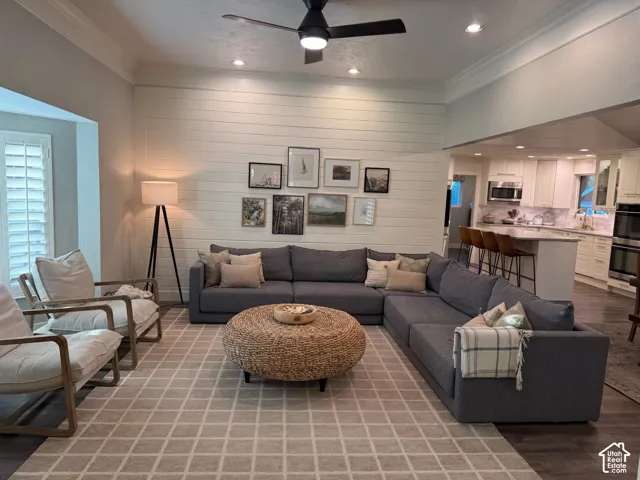 Living area with a shiplap accent wall, crown molding, and recessed lighting
