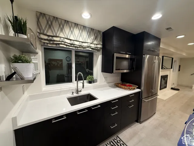 Modern kitchen featuring dark wood-finish cabinetry, stainless steel appliances, and a stainless steel undermount sink