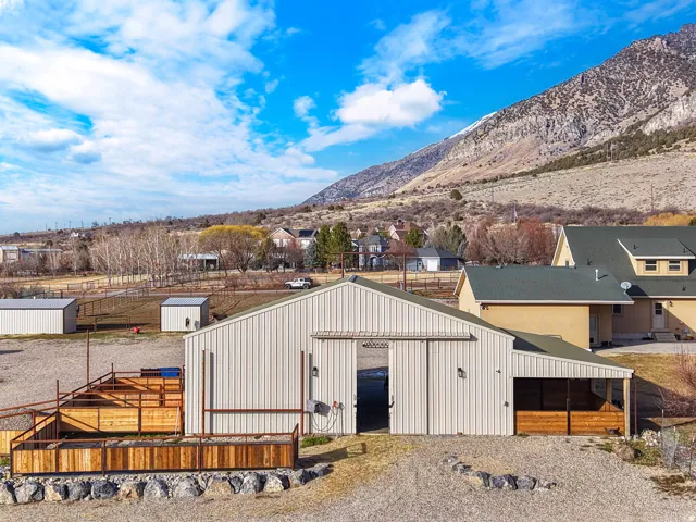 Metal-sided barn structure with a sliding barn door, an attached covered lean-to, and exterior wall-mounted lighting