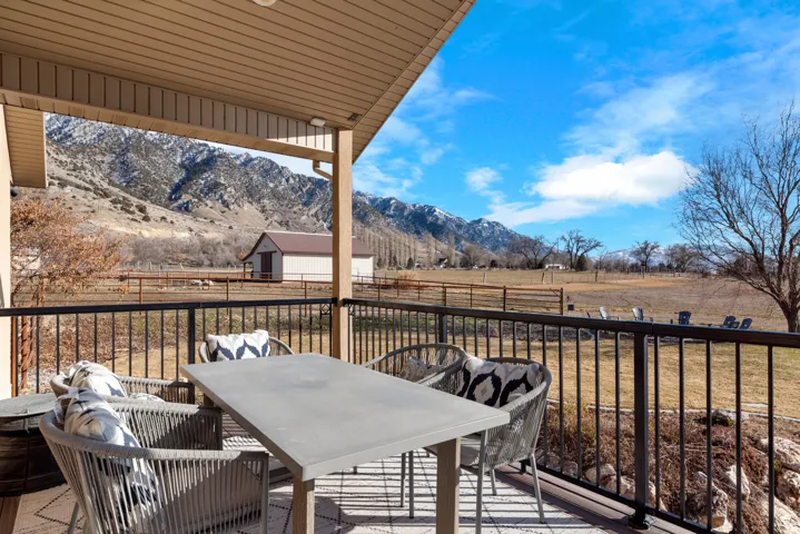 Covered outdoor deck with a dark railing and mountain backdrop