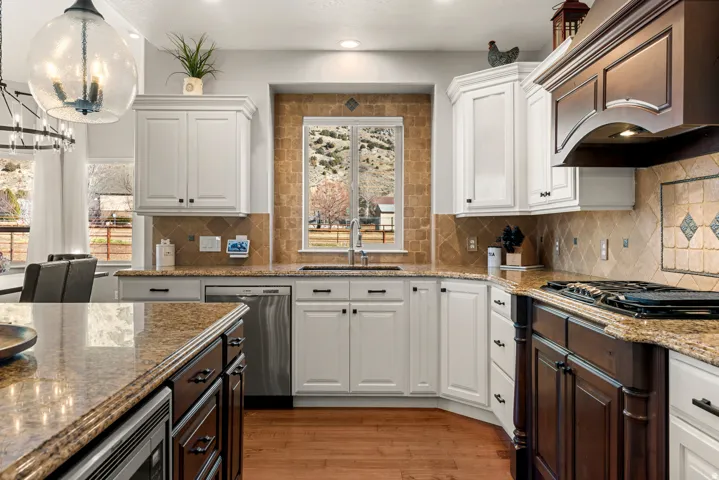 Kitchen featuring granite countertops, wood-finish flooring, white cabinetry, a built-in stainless steel dishwasher, and a gas cooktop