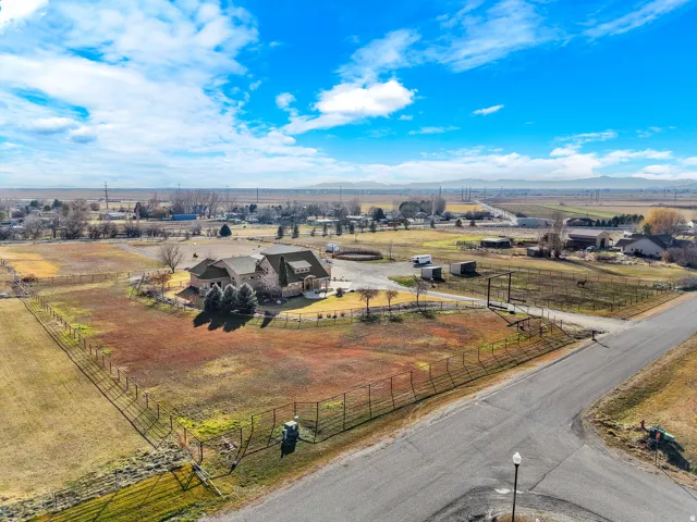 Expansive rural estate featuring a substantial main residence with multiple outbuildings, metal fencing, and manicured grounds encompassing several acres