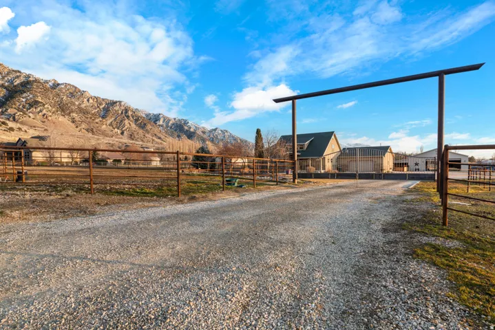Gravel driveway leading to the property, featuring a metal entry arch and metal perimeter fencing
