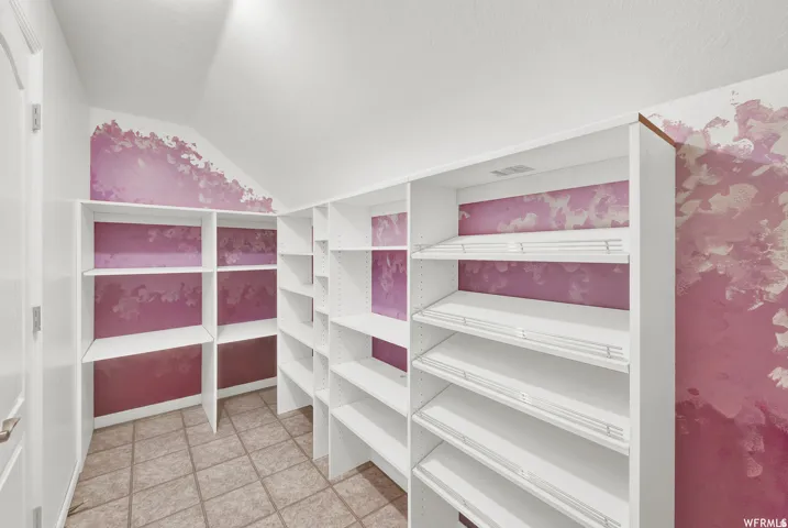 Expansive storage area featuring multiple white shelving units and tile flooring