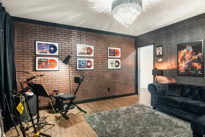 Exposed brick-finish wall, wood-finish flooring, and a crystal chandelier