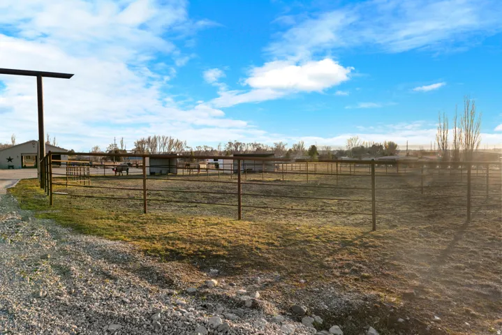 Expansive outdoor area with gravel drive, open fields, multiple fenced enclosures, and an outbuilding