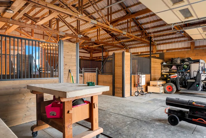 Open barn structure featuring exposed wood beams, a metal roof, and concrete flooring