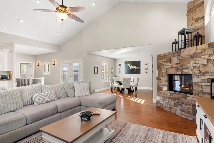Vaulted ceiling with a ceiling fan, recessed lighting, hardwood flooring, and a stone-clad fireplace