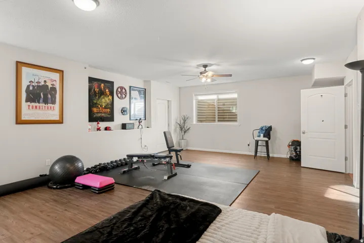 Wood-finish flooring throughout, recessed wall shelf, ceiling fan, white paneled doors, and a window with blinds