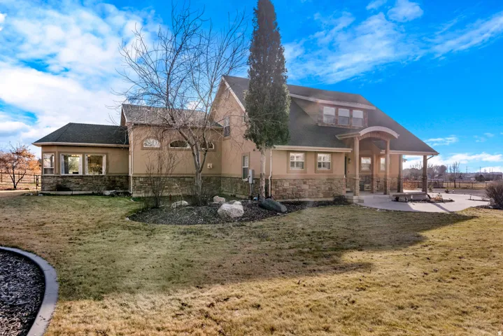 Stucco exterior with stone veneer accents, multi-level roofline, arched portico entrance, and dormer windows