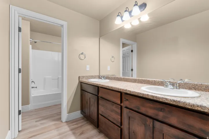 Double vanity with a speckled countertop, integrated sinks, and wood-finish cabinetry