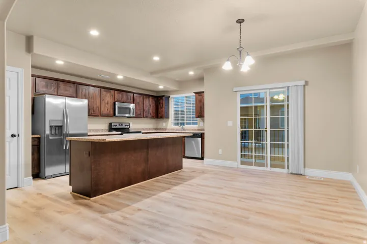 Expansive kitchen featuring wood-finish flooring, dark wood cabinetry, stainless steel appliances, and a central island