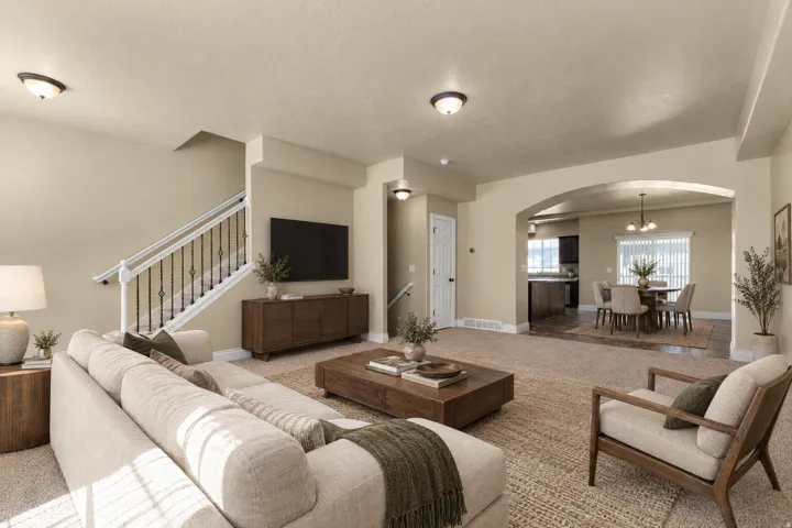 Expansive living area with neutral-toned walls, arched entryway, and carpet flooring