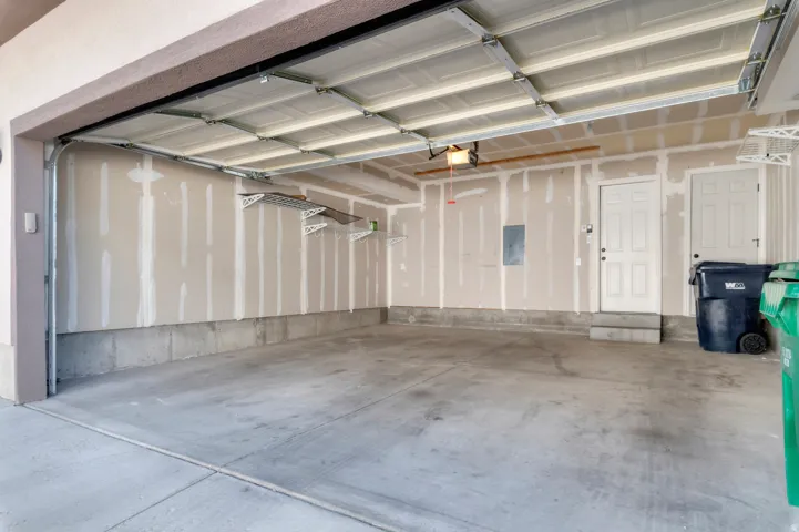 Attached multi-car garage with concrete flooring, automatic overhead door, and two interior access doors