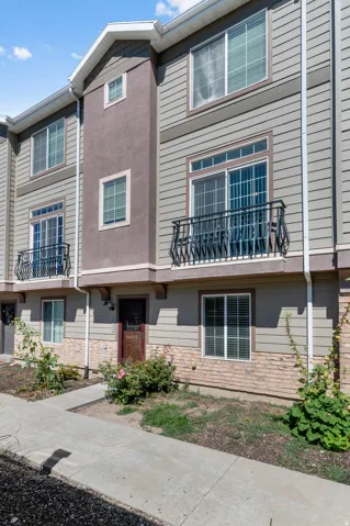Multi-level exterior featuring siding and stucco finishes, a ground-level entrance, and a balcony with an ornate metal railing