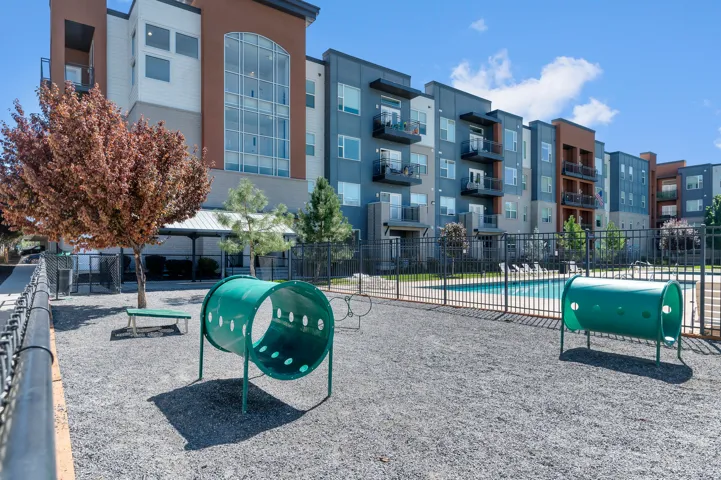 Gravel ground covering with green play tunnels, black metal fencing, and a swimming pool