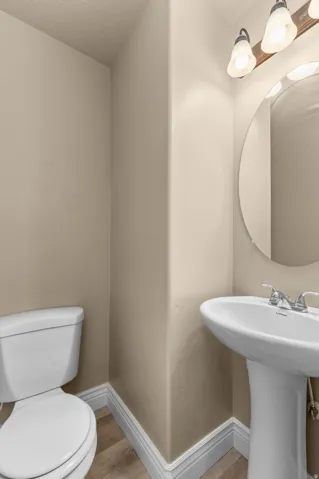 Pedestal sink with chrome faucet, circular mirror, and vanity lighting