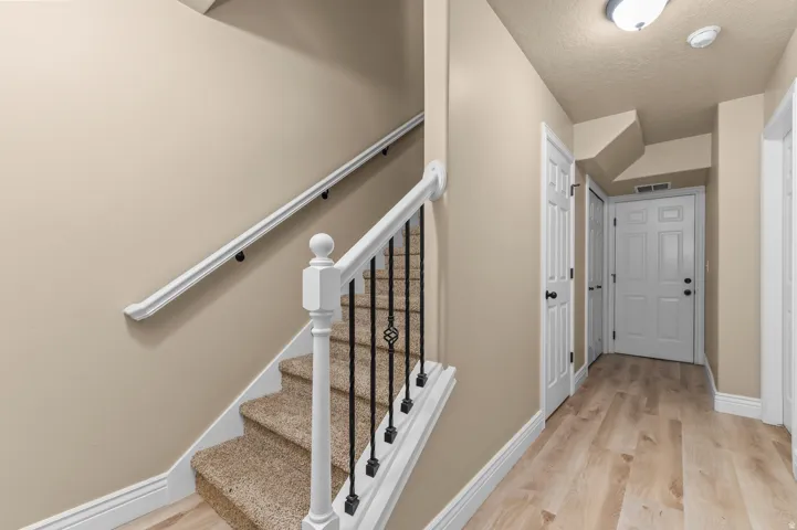 Carpeted staircase with an ornamental wrought iron railing and white newel posts