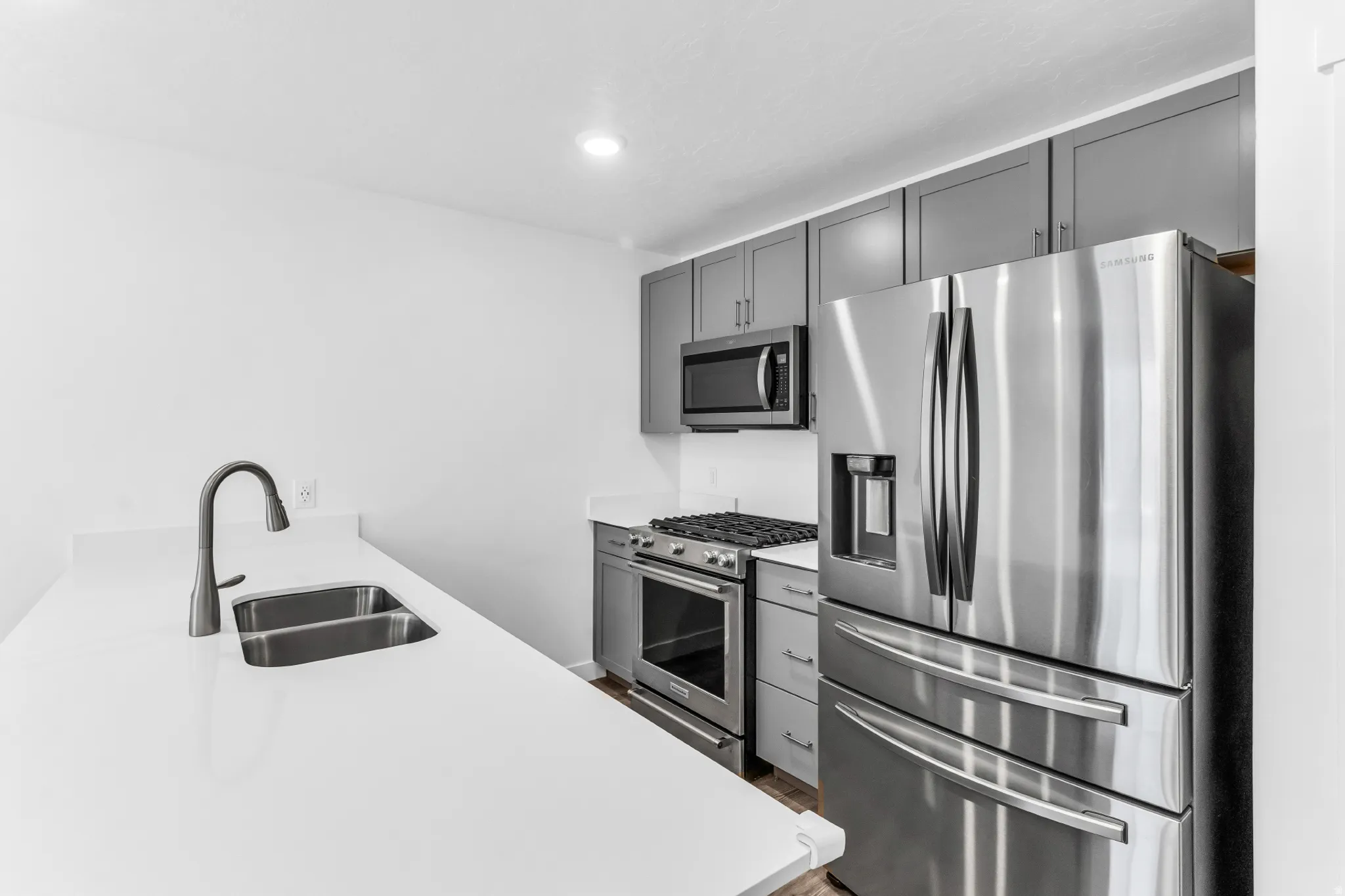 Quartz countertops, stainless steel appliances, dual basin sink, gray cabinetry, and recessed lighting