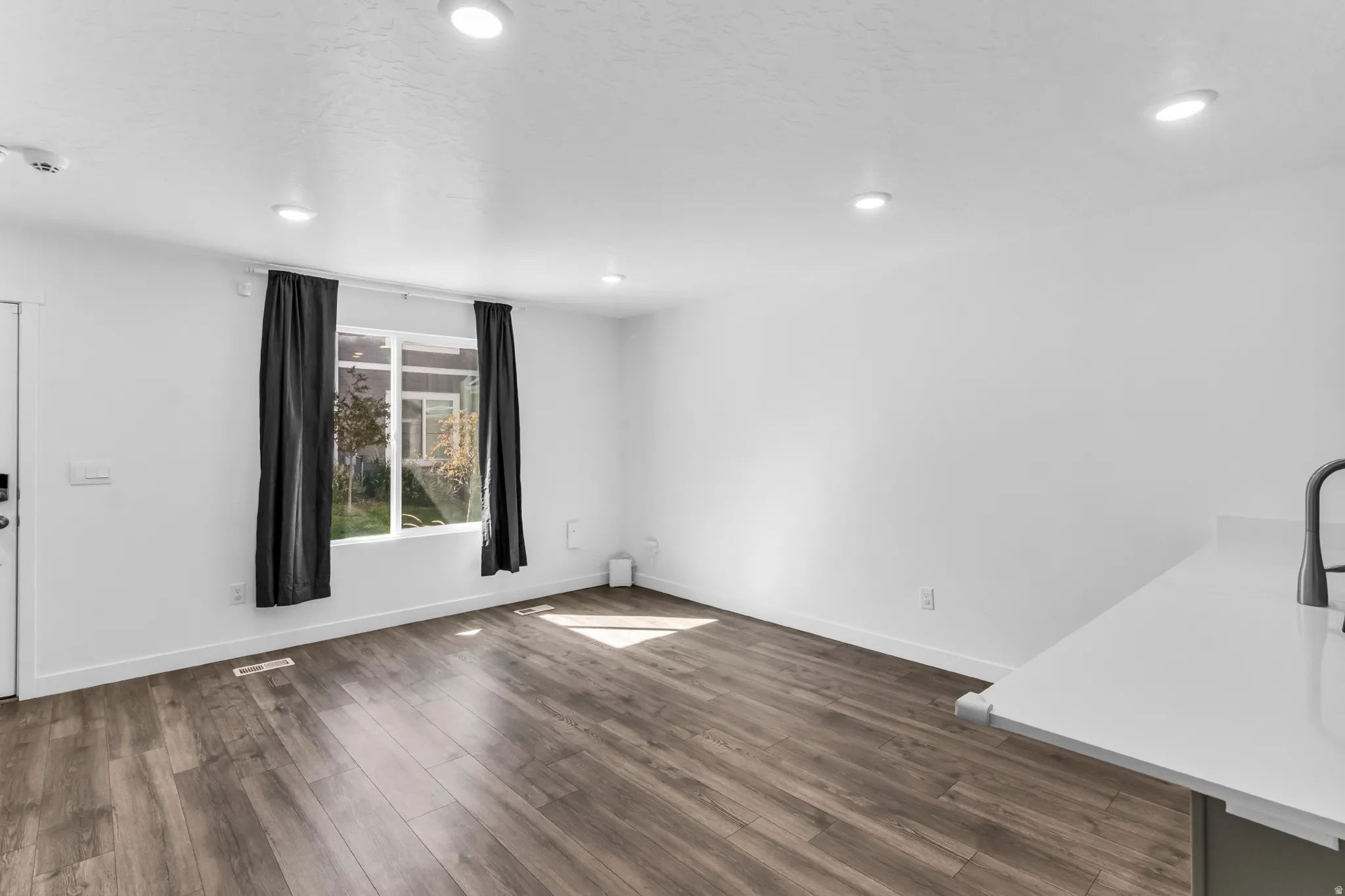 Spacious family room featuring beautiful laminate, white walls, recessed ceiling lighting