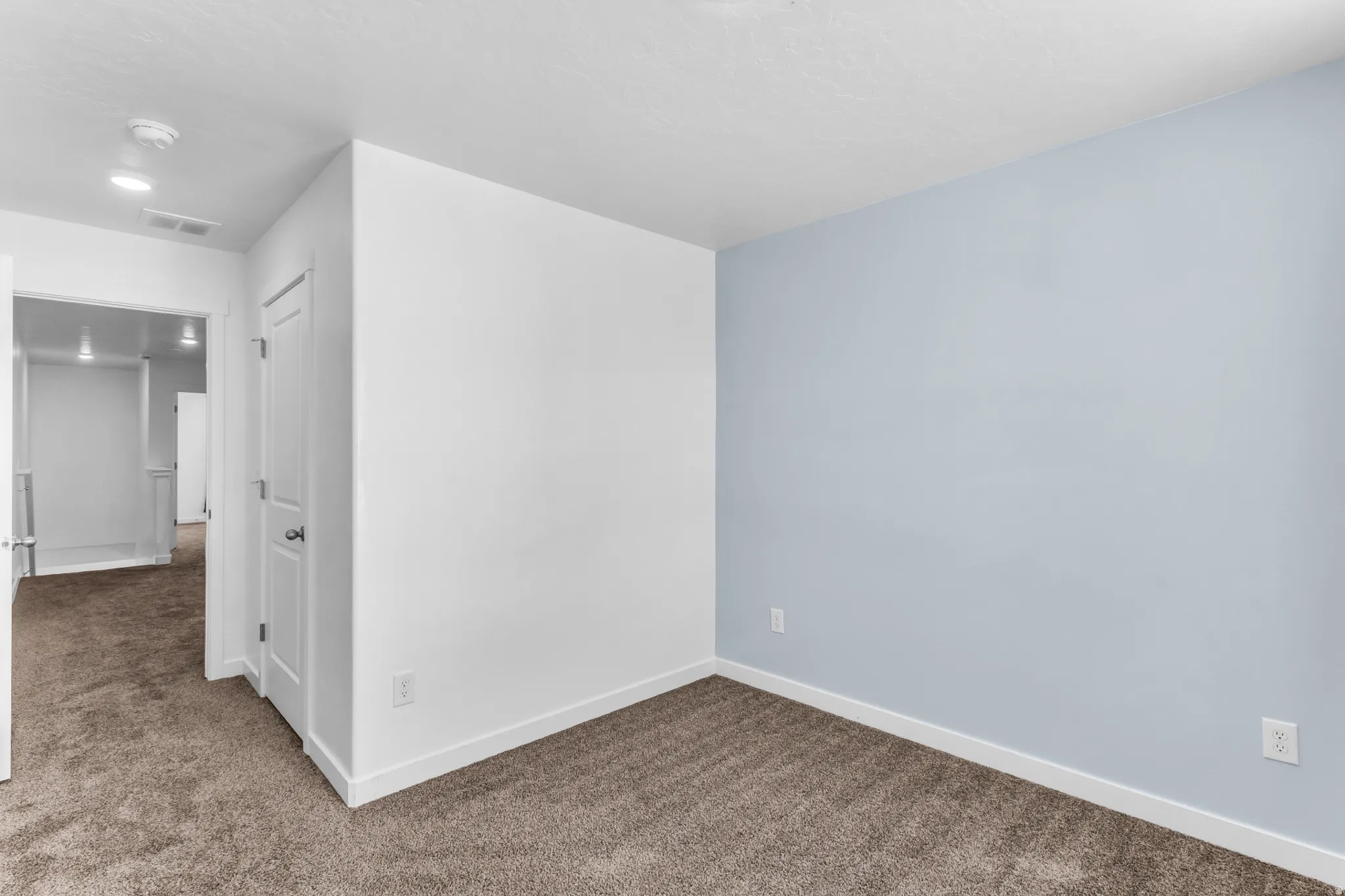 Carpeted room with a feature wall, recessed lighting, and a white interior door