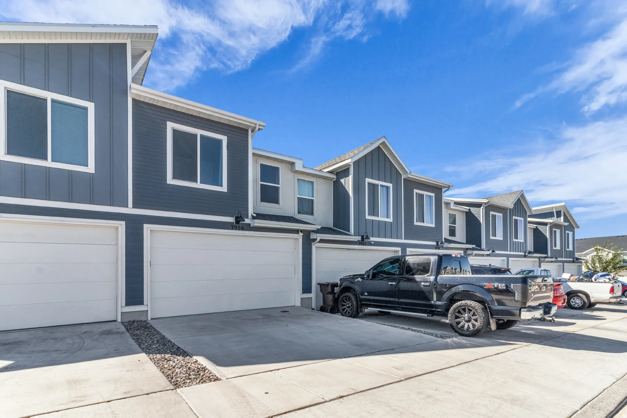 Contemporary exteriors featuring mixed siding, white-framed windows, attached 2 car garage with white doors, and concrete driveways