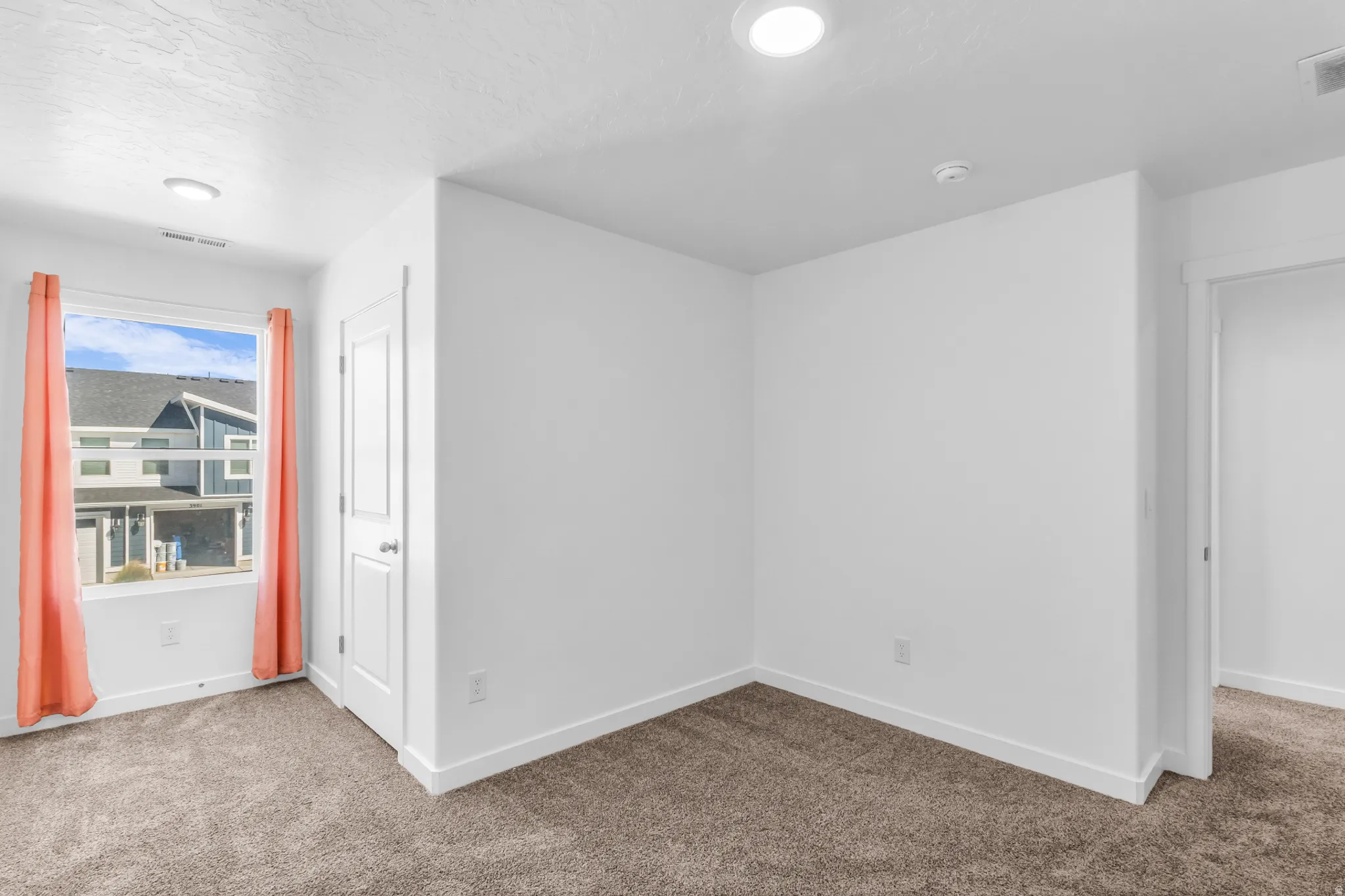 Recessed lighting, white walls, and neutral carpeting