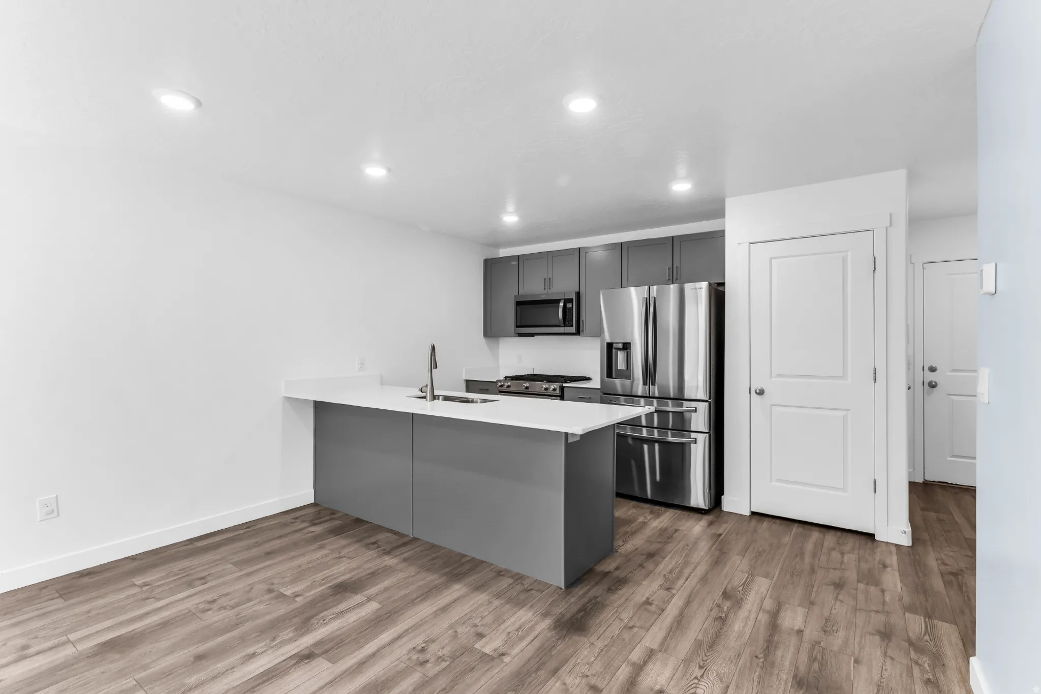 Kitchen featuring dark gray cabinetry, stainless steel appliances, a center island with a sink, quartz countertops ALL APPLIANCES INCLUDED