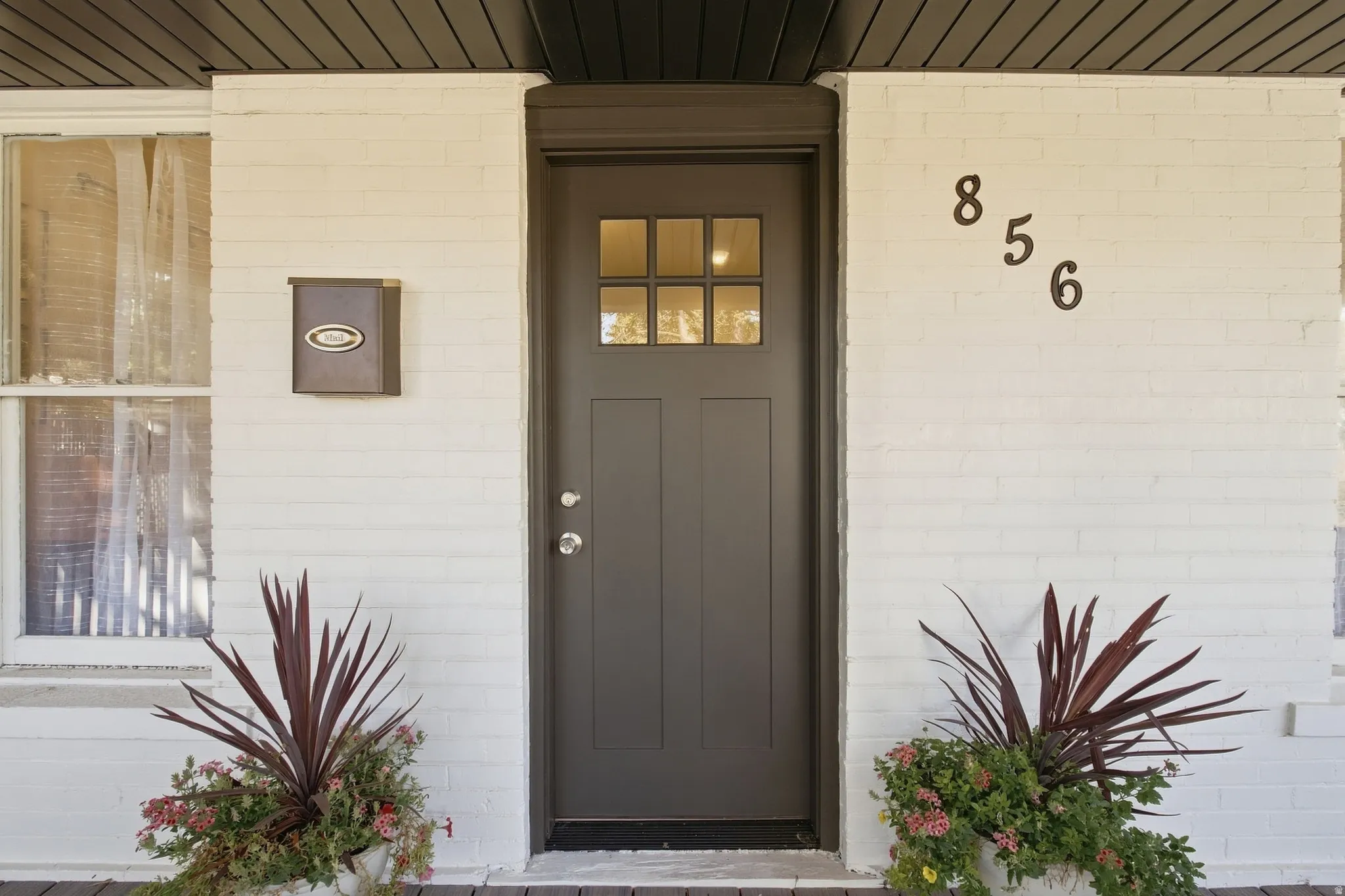Painted brick exterior with a dark-paneled front door, transom window, and prominent house numbers