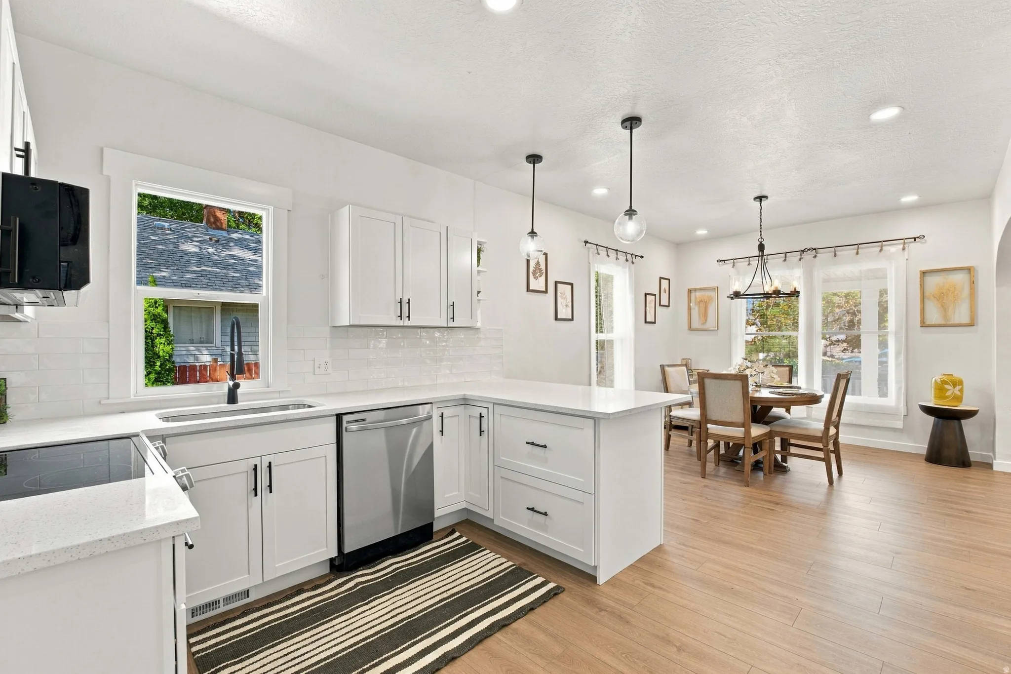 White cabinetry, stainless steel appliances, white subway tile backsplash, light wood-finish flooring, and recessed lighting