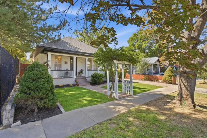 White exterior with a covered porch, white railing, and dark trim