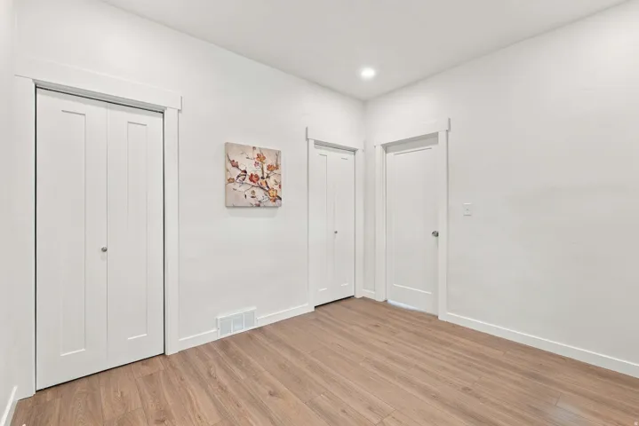 Wood-finish flooring, white walls, recessed ceiling lighting, and white trim