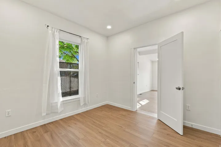 Wood-finish flooring, recessed lighting, and a white interior door with a modern handle