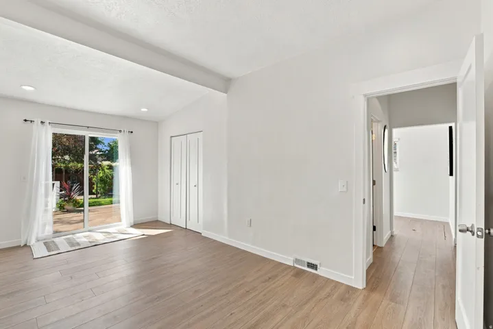 Vaulted ceiling with recessed lighting, wood-finish flooring, sliding glass patio door, and bi-fold closet doors
