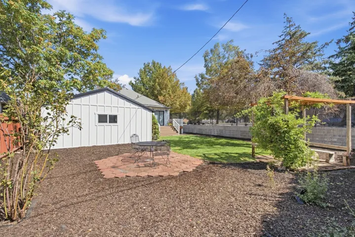 Spacious backyard featuring a brick patio, manicured lawn, and a wood pergola
