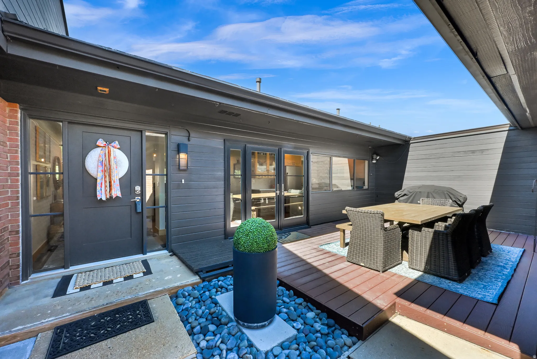 Private outdoor living area with a wood-finish deck, brick exterior, and modern exterior lighting
