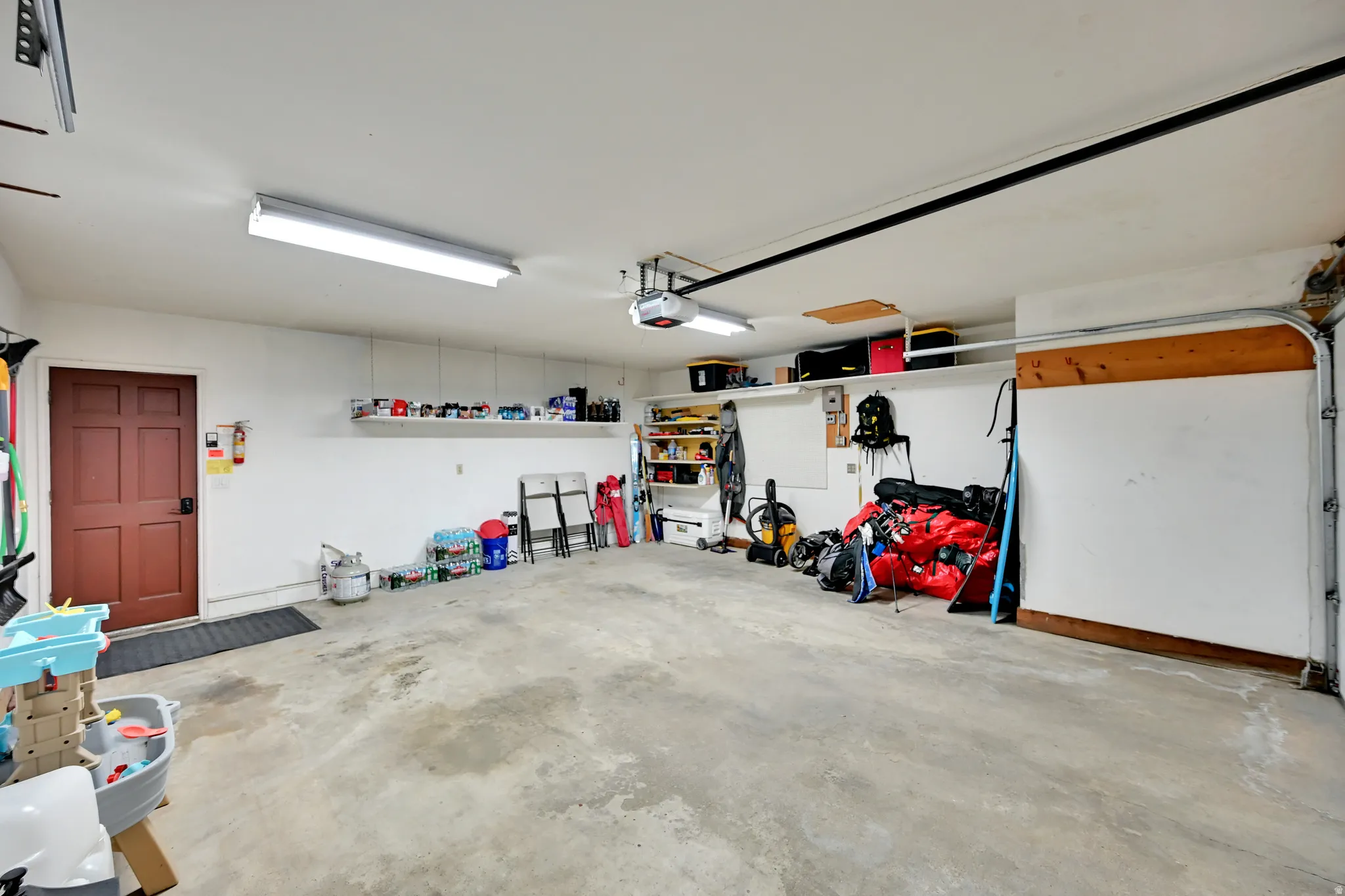 Spacious garage featuring a paneled door, overhead lighting, and an automatic garage door opener