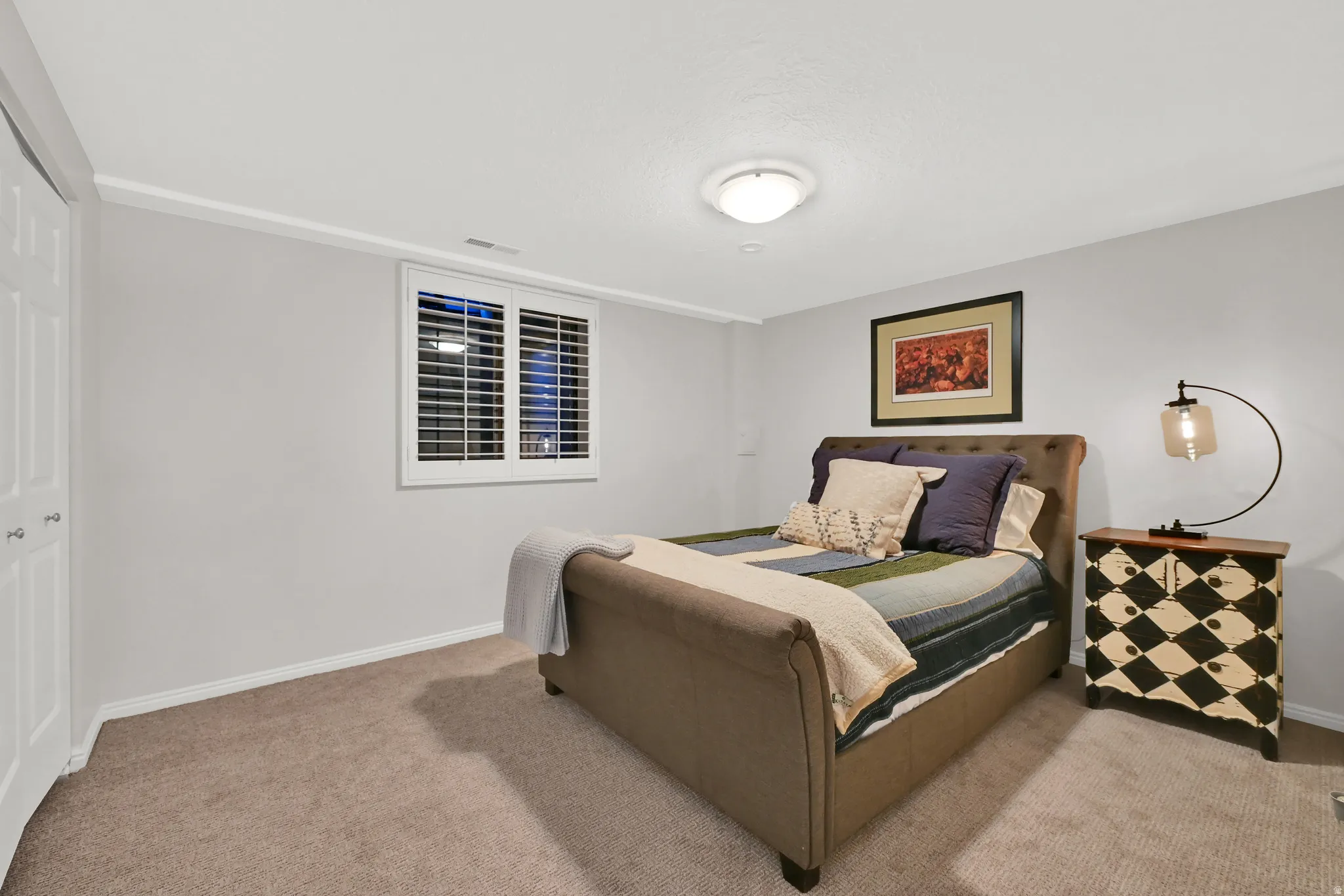 Interior space featuring neutral wall paint, white plantation shutters, white bi-fold closet doors, and carpet flooring