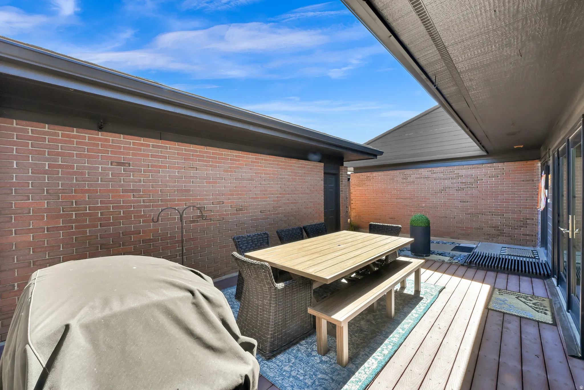 Private outdoor patio featuring brick walls and wood-finish decking