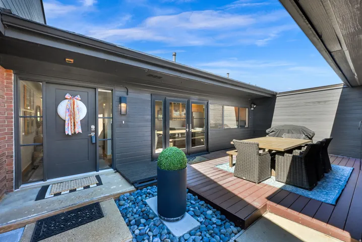 Private outdoor living area with a wood-finish deck, brick exterior, and modern exterior lighting