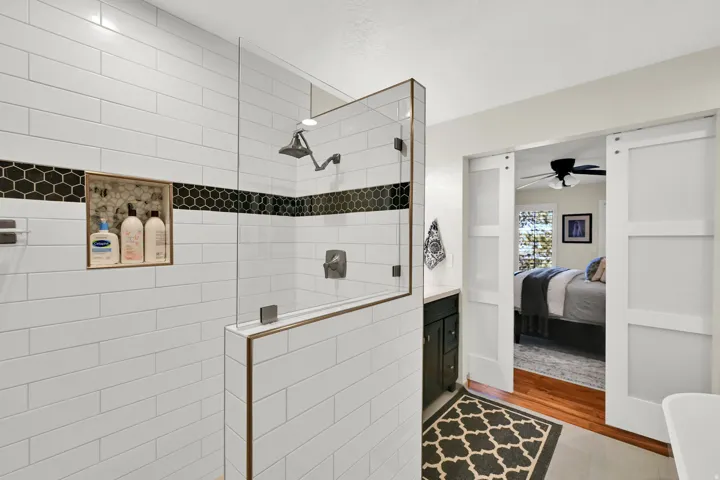 Glass-enclosed shower with white subway tile, a hexagonal tile accent band, and a built-in shower niche