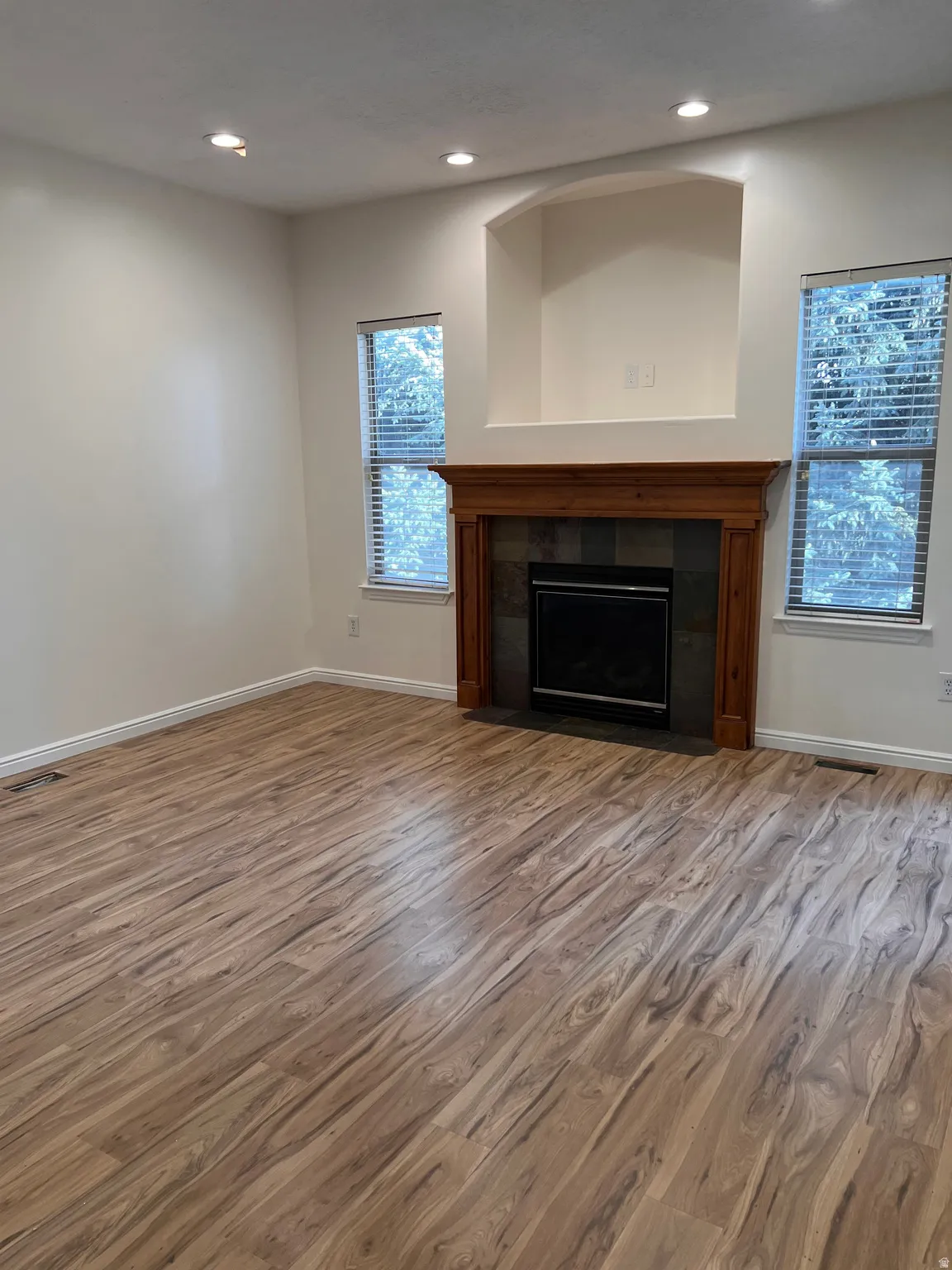New wood-finish flooring, new recessed lighting, new paint, fireplace with wood mantel, slate tile surround, and arched alcove