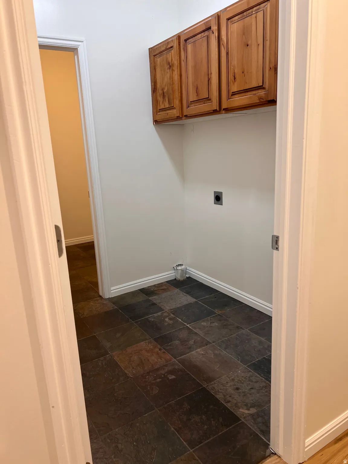 Laundry room with multi-toned square floor tiles and upper wood cabinetry